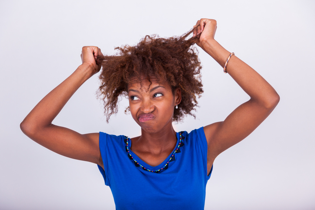 Young African American woman holding her frizzy afro hair